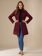 Front view of woman wearing a burgundy A-line wool coat with classic collar, buttoned up over a black jumper and jeans