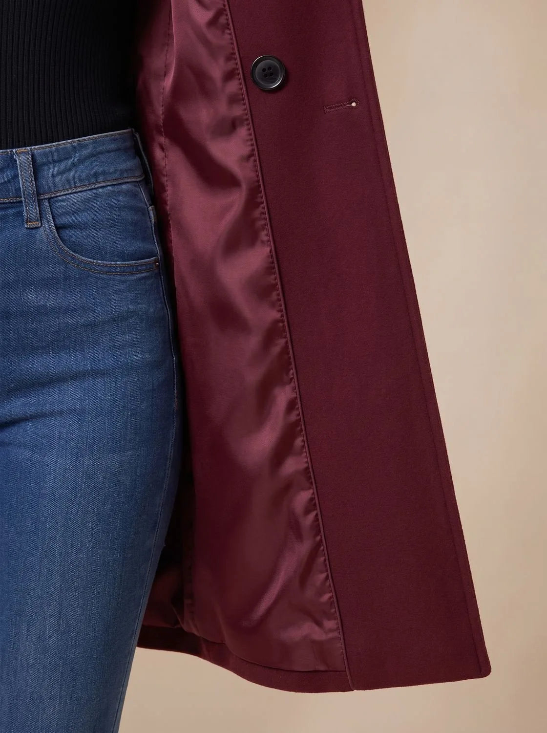 Detail view of coat collar and button placket showing the structured lapel and horn-style buttons