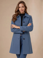 Blue wool coat with arms crossed, highlighting the fitted waist, structured collar and single-breasted button front