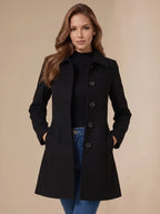 Black A-line wool coat with hands in pockets, showing the flared hem and full-length silhouette from the front