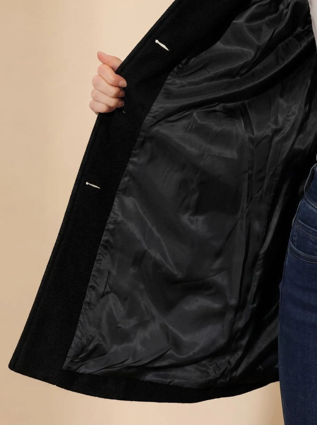 Close-up of black coat interior showing smooth satin-style lining and inside pocket detail