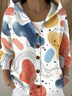 White hooded cardigan featuring abstract painterly shapes in coral, blue and mustard