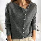 Close-up front view of a grey knit cardigan with an asymmetric collar and mother-of-pearl button placket