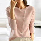 Model wearing a soft pink cardigan with off-centre neckline and matching cream trousers