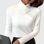 Close-up front view of a white asymmetric collar long-sleeve top paired with a black leather-look mini skirt