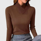 Woman wearing a brown fitted polo neck top with asymmetric wrap collar over a checked skirt