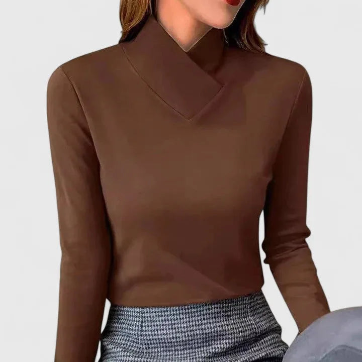 Woman wearing a brown fitted polo neck top with asymmetric wrap collar over a checked skirt