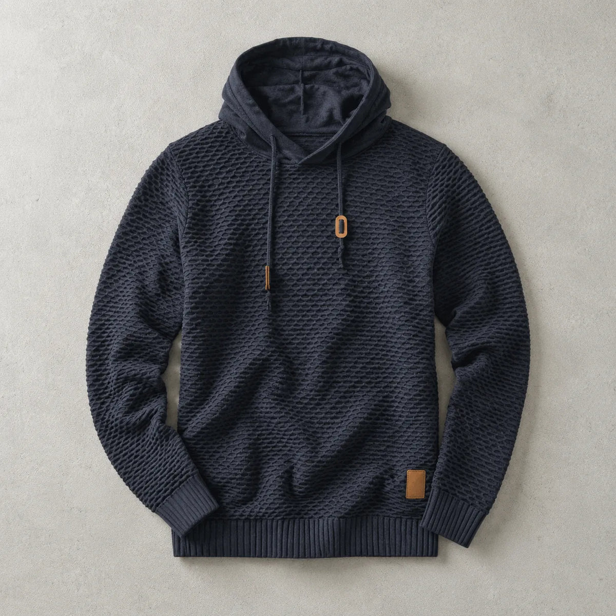 Navy basket-weave pullover hoodie laid flat, showing textured knit, lined hood and tan drawstring toggles