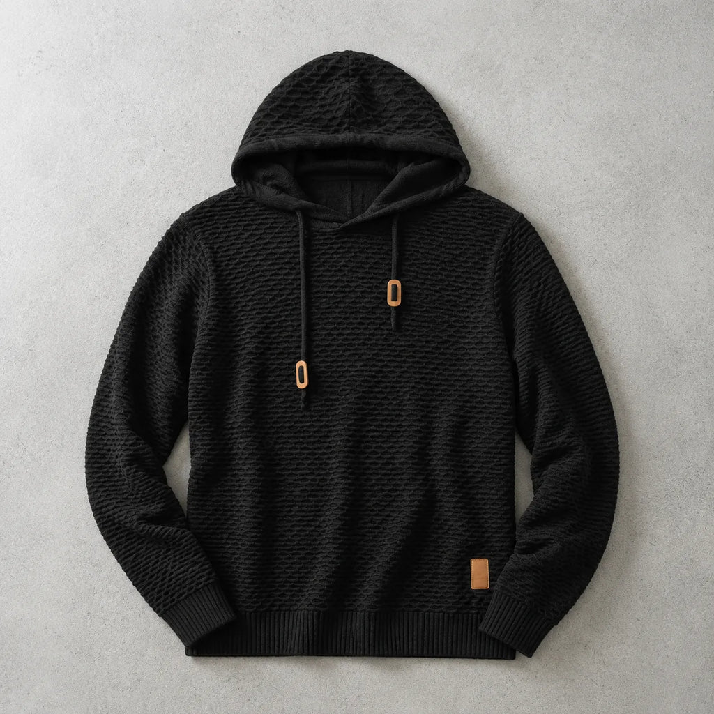 Black basket-weave knit hoodie laid flat with tan drawstring cord ends and ribbed trims