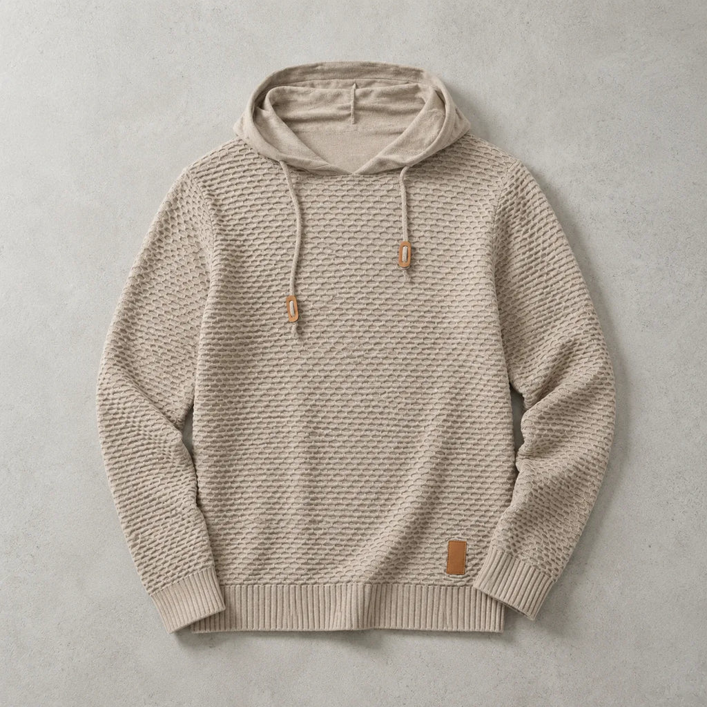 Beige knitted pullover hoodie laid flat, showing the raised basket-weave pattern and leather patch