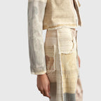 Close-up of cropped jacket and trouser waistband showing frayed pocket edges and mixed panel prints