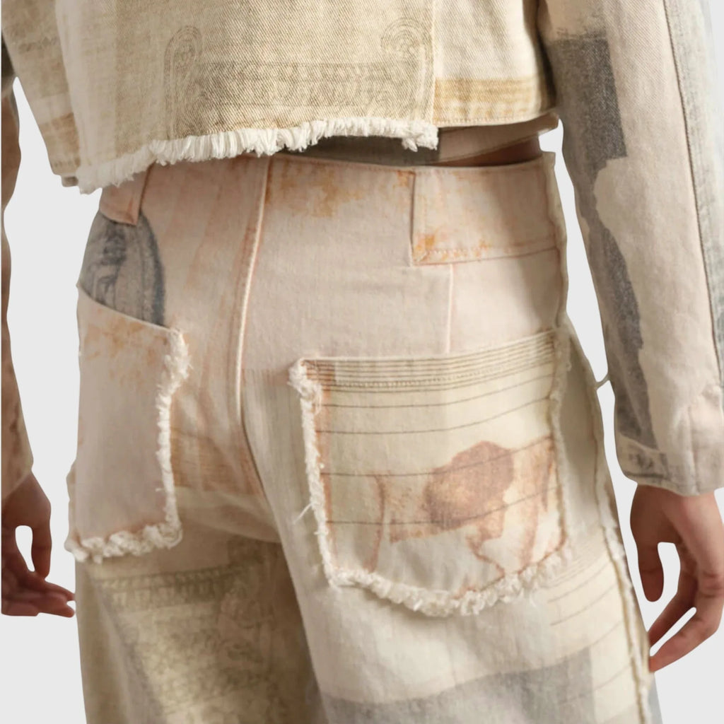 Close-up back view of frayed patch pockets with faded sketch and line motifs on beige fabric