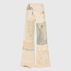 Detail of raw frayed hem at the ankle in soft beige tone with peeking yellow shoe