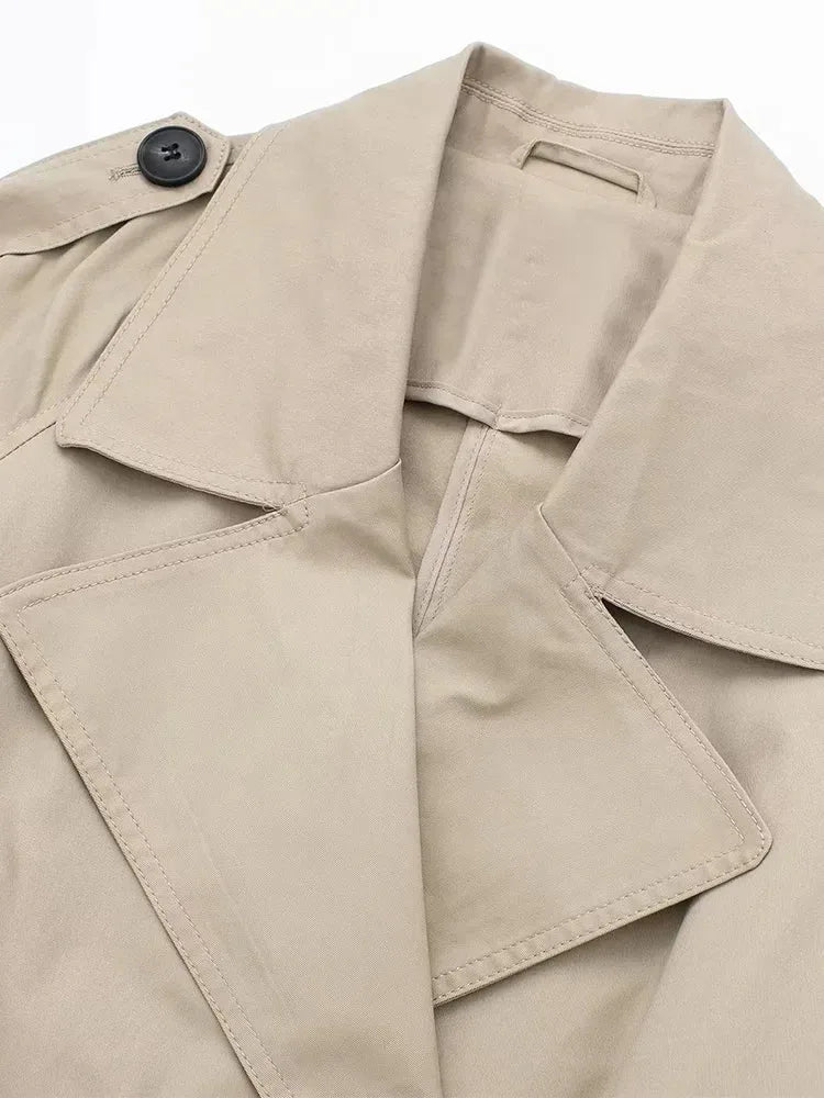 Close-up of the wide notched lapel collar and epaulette button on beige trench coat