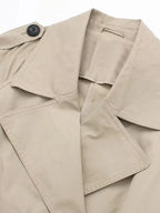 Close-up of the wide notched lapel collar and epaulette button on beige trench coat