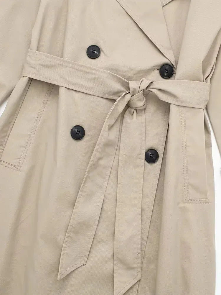 Close-up of the double-breasted button placket and hand-tied waist belt on beige trench coat