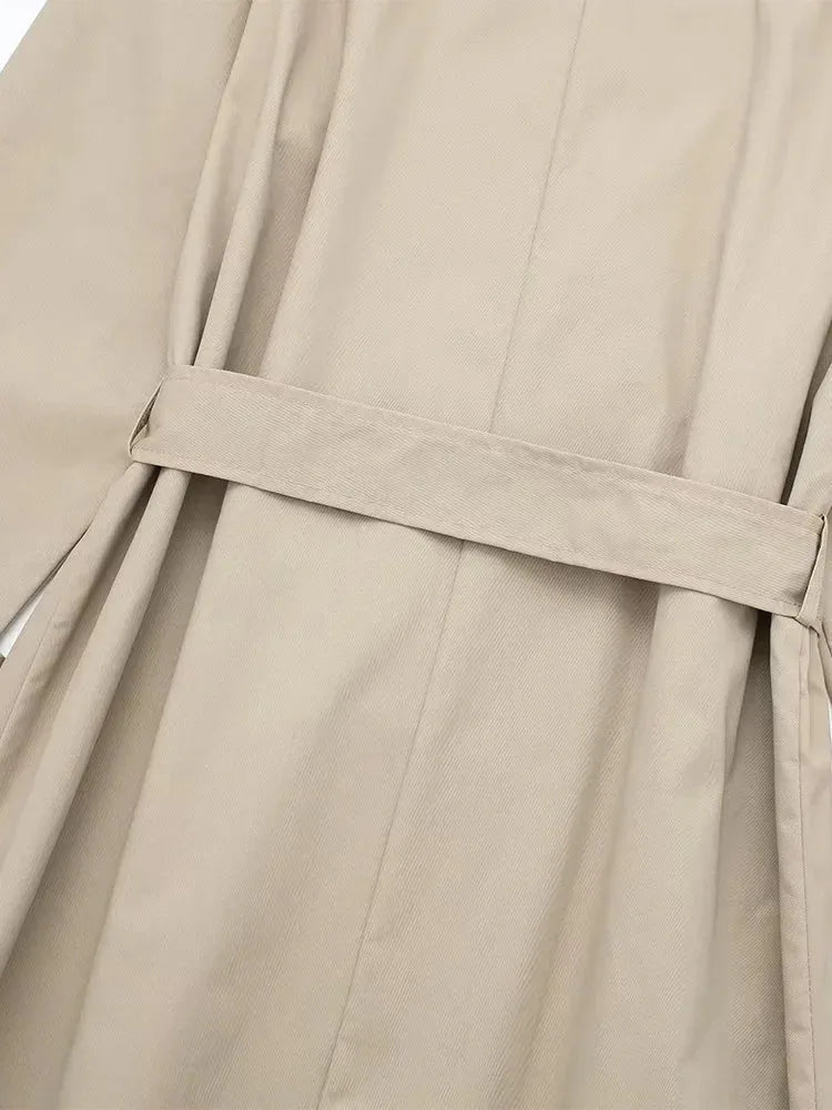 Close-up of the back waist belt strap and vertical seam detailing on beige trench coat