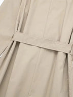 Close-up of the back waist belt strap and vertical seam detailing on beige trench coat