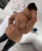 Close side view of a brown puffer jacket showing the quilted panels and tied belt detail