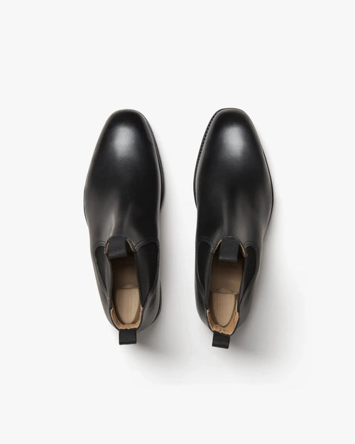 Overhead view of a matched pair of black leather Chelsea boots fitted with wooden shoe trees to show shape and elastic gussets