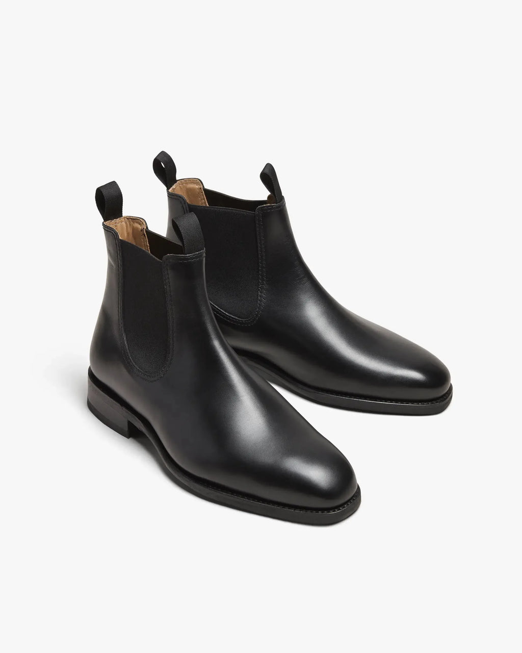Three-quarter angle of both black leather Chelsea boots side by side, highlighting the smooth finish and stacked leather sole
