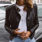 Model wearing the quilted-shoulder leather biker jacket outdoors, unzipped, with denim jeans and a parked car behind her