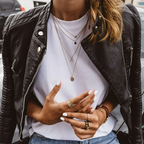 Close-up of the open jacket revealing the white tee, layered necklaces and the jacket's silver zip pocket detail