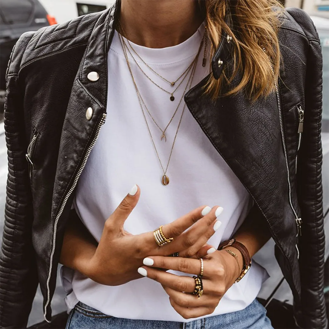 Close-up of the open jacket revealing the white tee, layered necklaces and the jacket's silver zip pocket detail