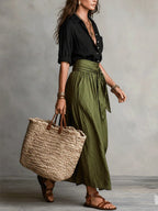 Side profile view of the black shirt tucked into the belted olive green skirt with layered gold necklaces