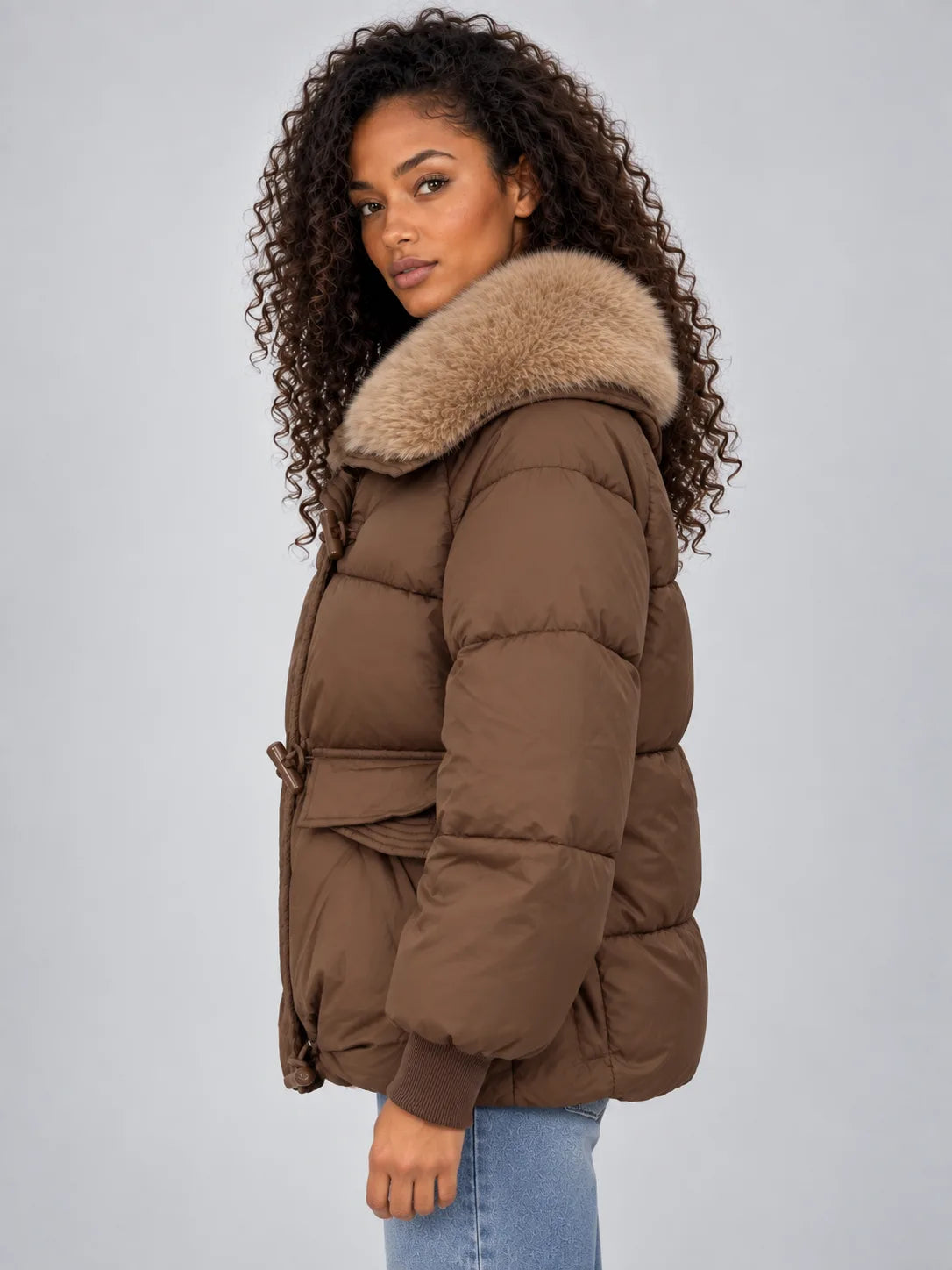 Side profile highlighting the relaxed fit, drawstring waist toggle and oversized flap pocket of the brown coat