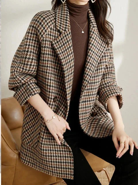 Front view of a woman wearing a brown houndstooth checked wool blazer over a brown polo neck jumper