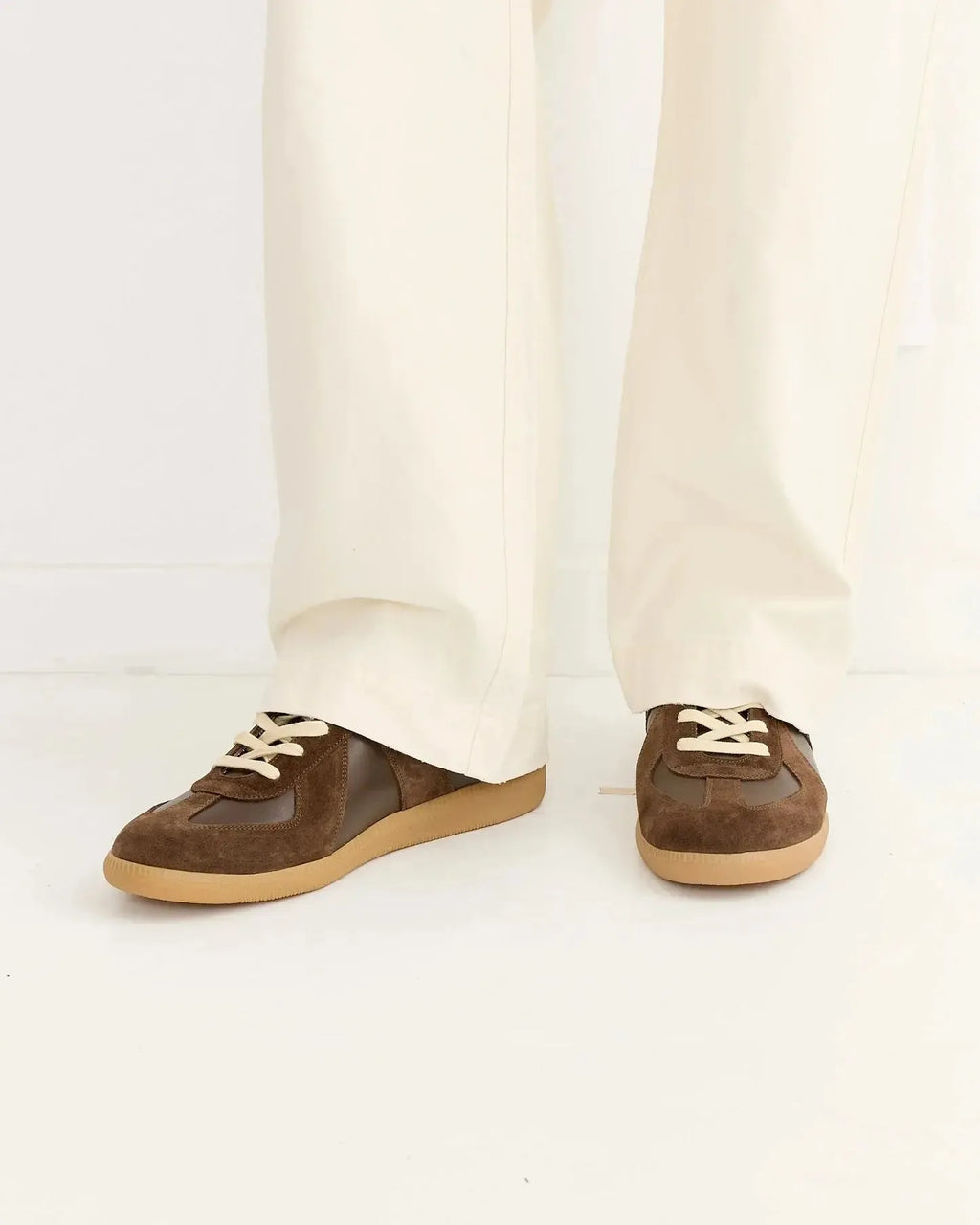 Front view of the trainers worn with cream turned-up trousers