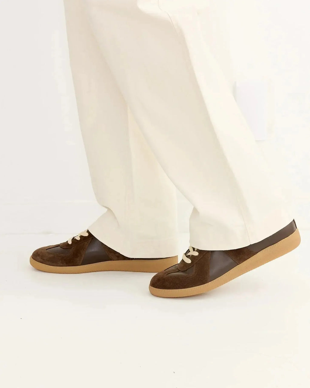 Side angle of the trainers worn while walking, paired with cream trousers