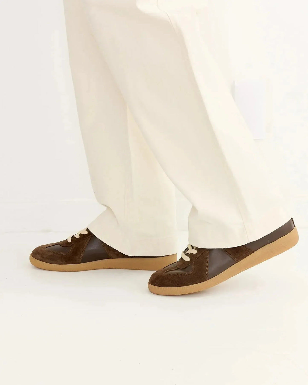 Side angle of the trainers worn while walking, paired with cream trousers