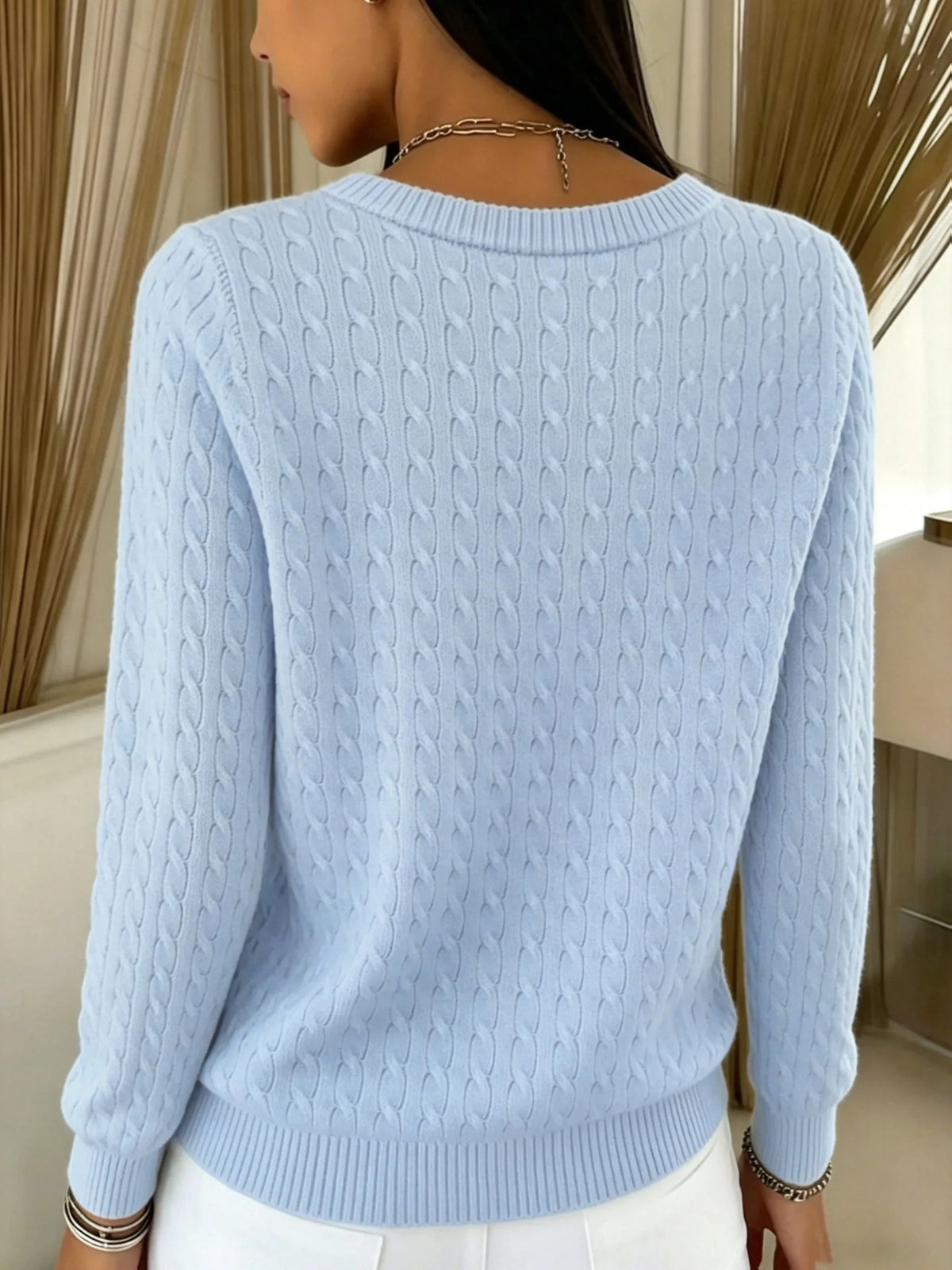 Back view of light blue cable knit cardigan highlighting the ribbed crew neckline and knit detailing