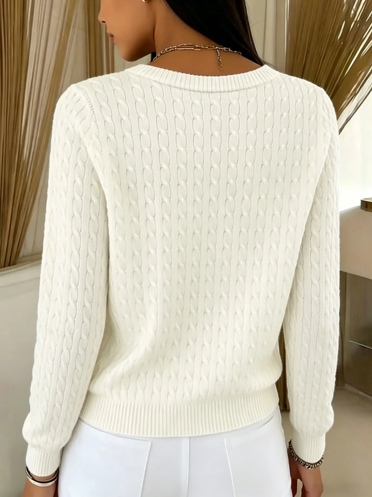 Back view of cream white cable knit cardigan showing continuous cable-knit pattern down the sleeves