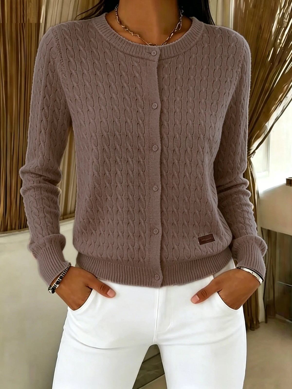 Coffee brown cable knit cardigan fully buttoned, front view with hands in trouser pockets