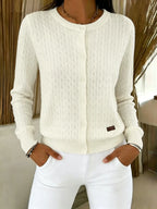 Close-up of light blue cable knit cardigan showing button placket and cable-knit stitch detail