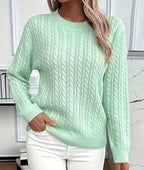 Front view of mint green cable-knit crew-neck jumper with ribbed cuffs, worn with white trousers