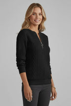 Three-quarter angle of a black zip-neck jumper highlighting the raised cable knit texture across the chest