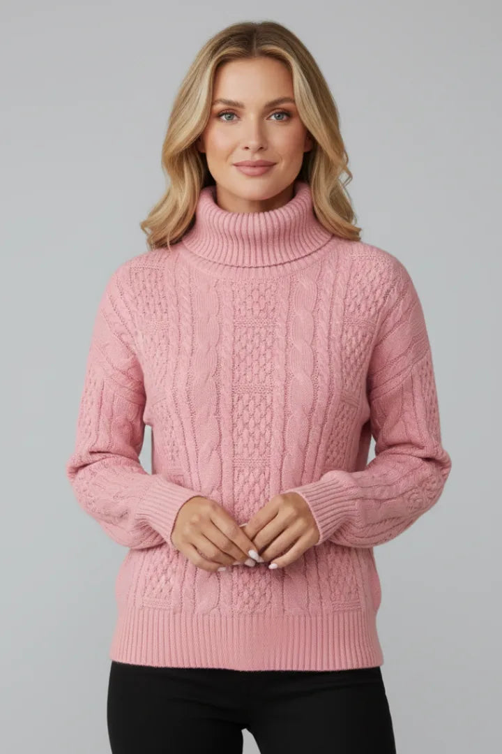 Front view of a pink cable knit jumper with a folded polo neck collar, worn with black trousers