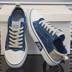 Pair of blue canvas trainers with cream laces and contrast heel panel, shown resting against the shoebox