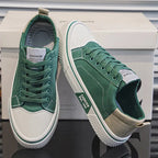 Green canvas trainers with white toe cap and beige heel tab, side by side on top of the shoebox