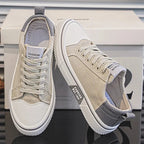 Beige and grey canvas trainers with white sole, one shoe standing and one tipped on its side
