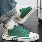 Close-up of a person wearing a green canvas trainer with rolled-up jeans and ribbed socks