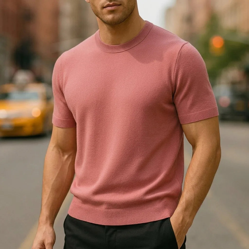 Dusty pink short-sleeve knitted T-shirt with ribbed cuffs, worn with black trousers on a city street