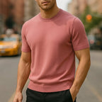 Dusty pink short-sleeve knitted T-shirt with ribbed cuffs, worn with black trousers on a city street