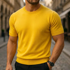 Mustard yellow short-sleeve knitted T-shirt with ribbed collar, paired with black trousers and a wristwatch