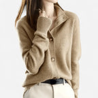 Close-up of a camel cashmere cardigan with notched collar, wooden buttons and ribbed cuffs worn over a black belt