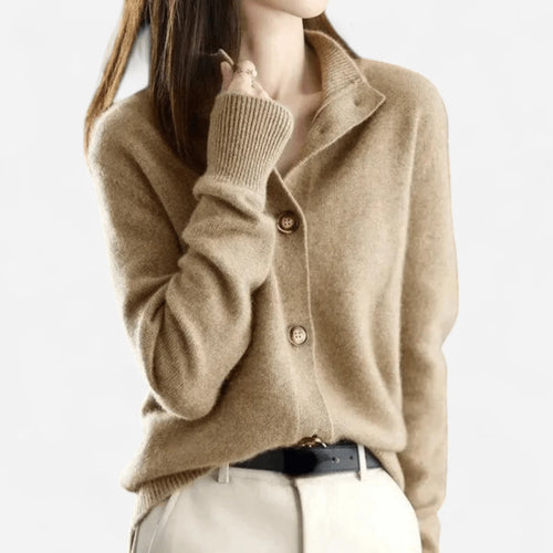 Close-up of a camel cashmere cardigan with notched collar, wooden buttons and ribbed cuffs worn over a black belt
